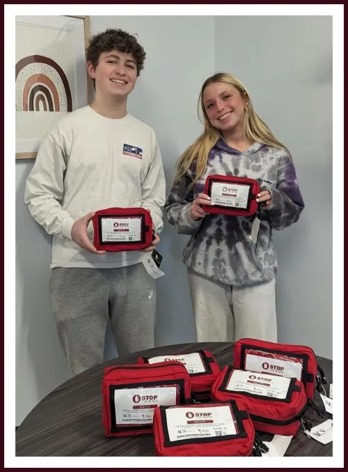 Zander Bauer and Elijah Falkenstein holding Stop the Bleed kits at Staples High School